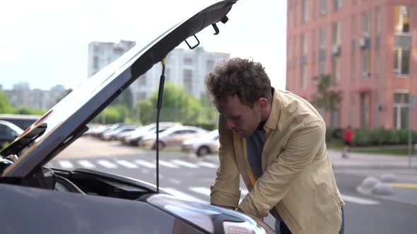 Young, attractive man opened the hood of the car