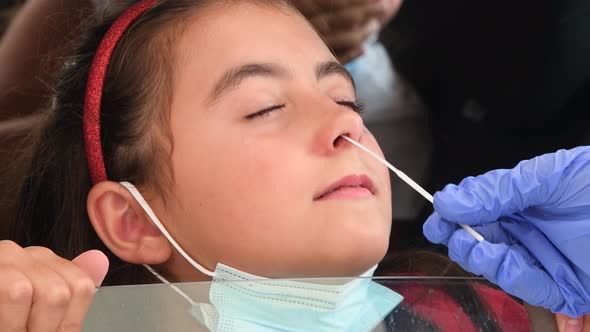 Pediatrician Taking Nasal Mucus Test Sample From Elementary Age Girl's Nose Performing Respiratory