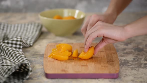 Cut canned peach on a wooden cutting board.	