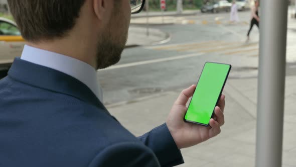 Businessman Looking at Smartphone with Green Chroma Screen