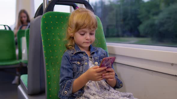 Little Girl on Smartphone Chatting Texting Browsing Social Media While Traveling By Bus in City