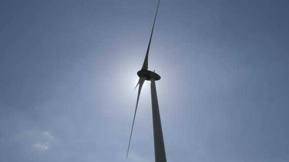 Wind turbine in operation against a background of blue sunny sky. the silhouette of the wind turbine