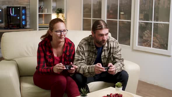 Man and Woman Sitting on Sofa Playing Video Games