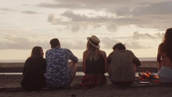 Rear View of Friends Sitting on Beach in Evening