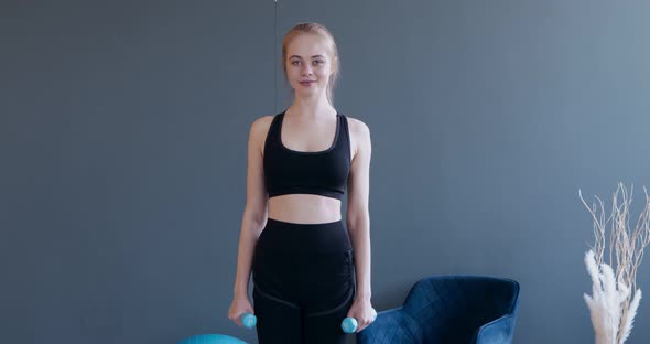 Young Woman Making Biceps Exercises with Dumbbells