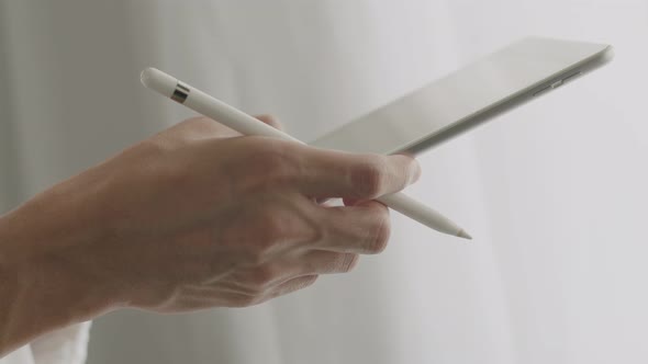 Close-up businessman signing a digital contract on a tablet.