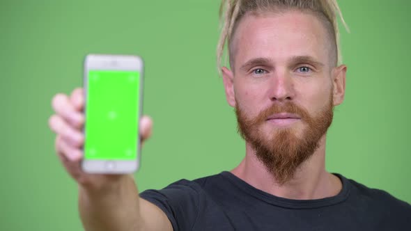 Happy Handsome Bearded Man with Dreadlocks Showing Phone