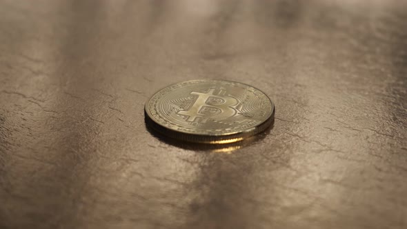 Bitcoin Coins Are Closeup Rotating on a Gold Table