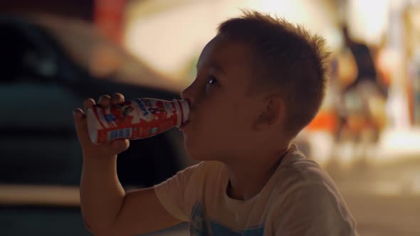 Hungry child drinking yoghurt outdoor at night