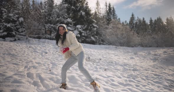 Woman Playing Winter Game Throwing Snowball in Mountain Forest Outdoors