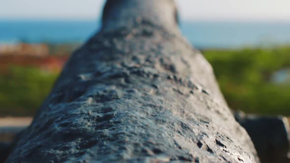 POV Tilt up reveal shot, historic cannon pointed out over a bay on the Caribbean Sea at Willemstad,