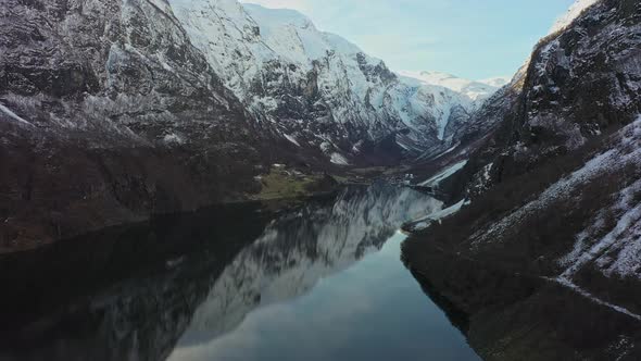 Beautiful aerial flying in unesco listed Naeroyfjord towards Gudvangen - Snow capped tall mountains