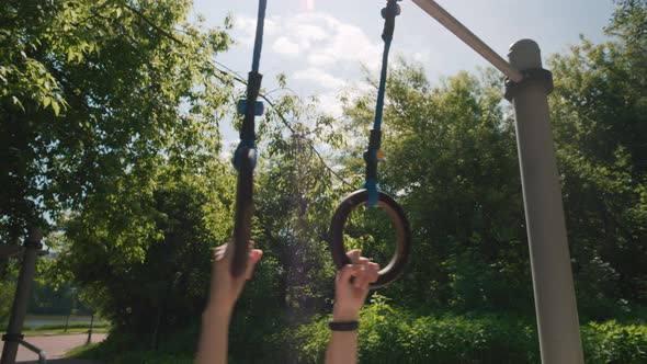 Closeup of Woman Hands Hanging and Swinging on Gymnastic Rings Back and Forth