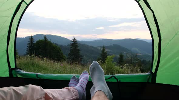 View of the Legs of Tourists Resting in a Tent a Couple in Love Climbed to the Top of the Mountain