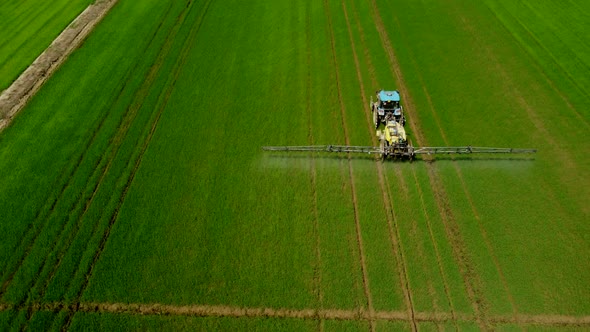 Tractor and Farmer Spraying Fertilizer, Herbicide, Pesticide on Agriculture Farm Field