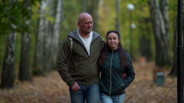 Loving Husband and Wife Are Embracing and Walking in Picturesque Alley in Autumn Park, Medium