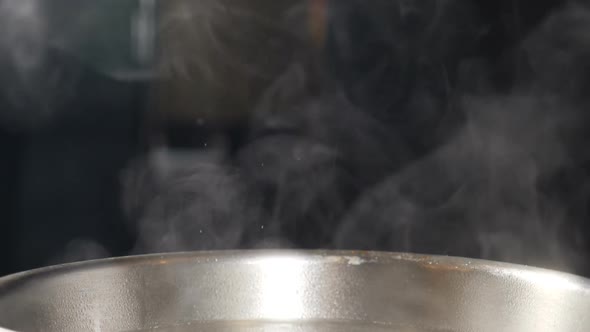 White Smoke in Slow Motion Rising Above Hot Frying Pan on Black Background. Cooking in Restaurant