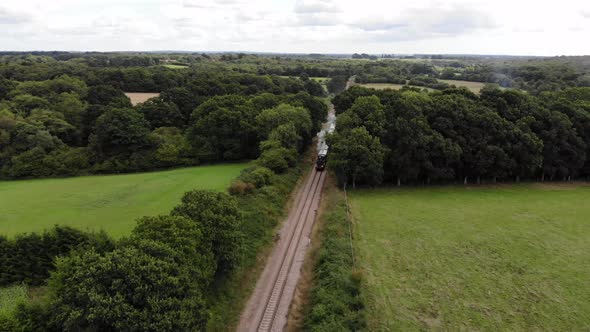 Steam Train crossing English countryside on old railway line. 4K Aerial drone footage