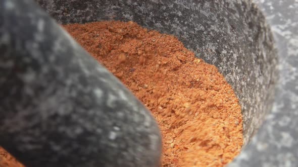 Closeup of Heavy Pestle Grinding and Mixing Spices Peppers and Sea Salt