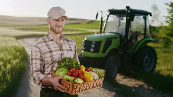 A Farmer is Standing Near a Field and Holding a Basket of Vegetables From the Field