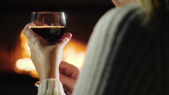 Hand with A Glass of Wine of A Woman Who Is Relaxing by The Fireplace