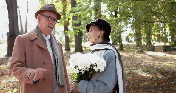 Elegant Elderly Woman with Bouquet of Flowers Having Fun Talk with Cavalier