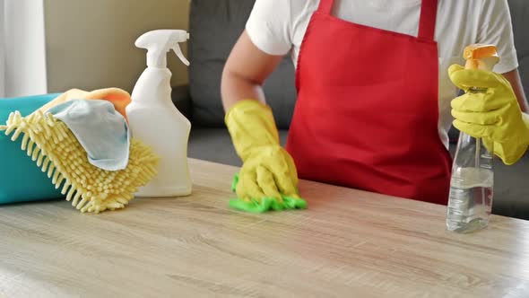 Woman in an Apron and Protective Gloves Washes and Polishes the Countertop Thoroughly