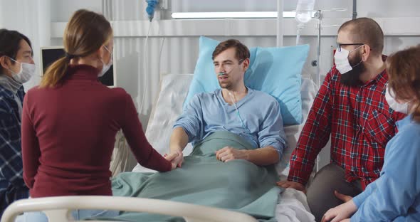 Family and Friends Visiting and Cheering Patient in Hospital Ward