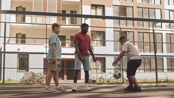 Dad with Sons Having Fun with Football Outdoors