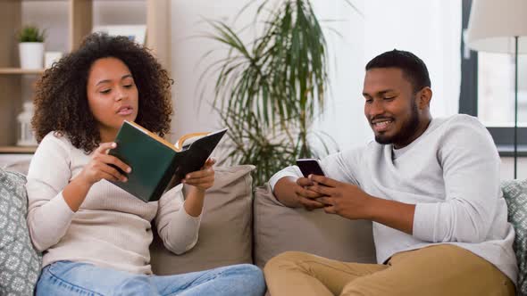 Happy Couple with Smartphone and Book at Home