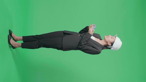 Side View Of Female Engineer Looking Around While Using Smartphone In The Green Screen Studio