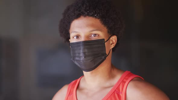 Portrait of fit african american man exercising in city wearing face mask in the street