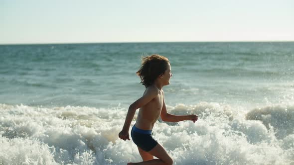 Side View of Happy Caucasian Little Boy Running Along Coastline