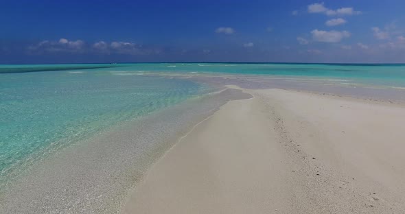 Daytime fly over clean view of a sandy white paradise beach and blue ocean background in colourful 4