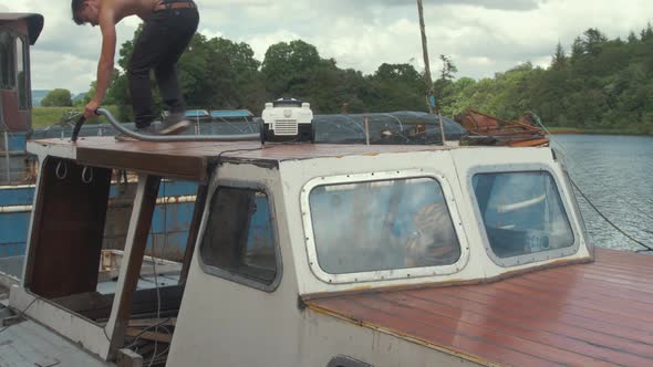 Topless carpenter hoovering sanded boat cabin roof