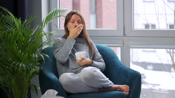 Unhealthy Woman Sits in a Chair and Coughs Because She Has a Cold Flu Coronavirus