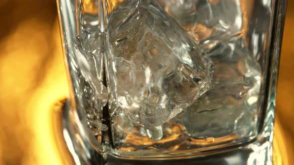Super Slow Motion Macro Shot of Pouring Whiskey Into Glass with Ice Cubes at 1000 Fps