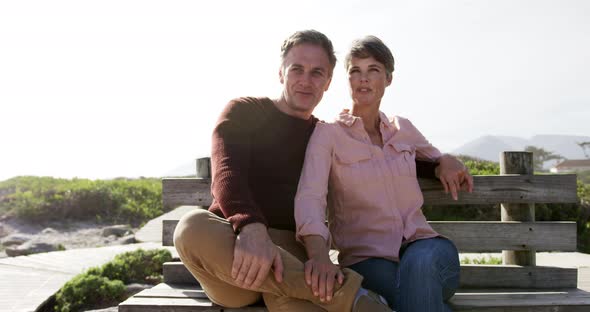 Caucasian couple enjoying free time by sea on sunny day sitting on bench