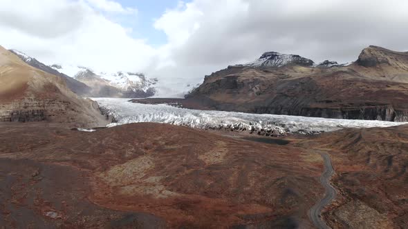 Wide Aerial Shot of a Dirt Road Leading Up to a Glacier.