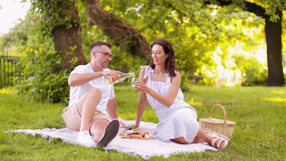 Happy Couple with Wine Having Picnic at Park