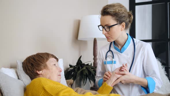 Female Doctor Examining Senior Patient's Pulse. Elderly Care And Assistance Concept.