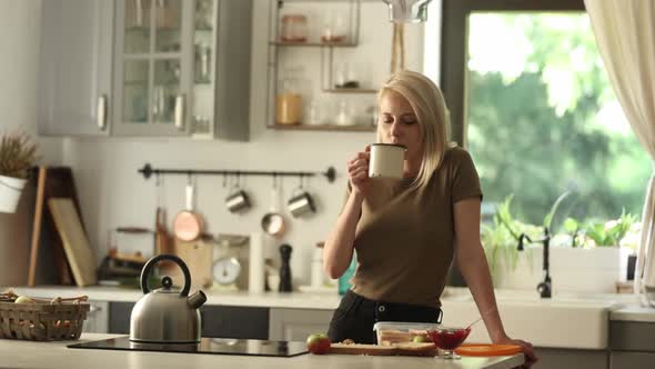 blonde woman in the kitchen with a cup of coffee