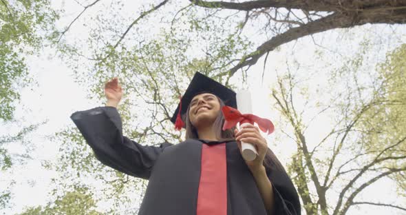 Beautiful Brunette Woman Standing in Park Putting Off Mortarboard Throwing Smiling