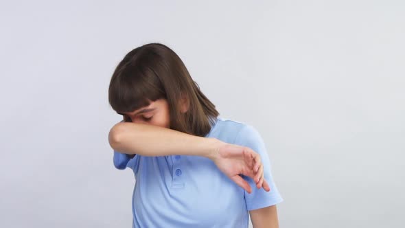 Young Female Sneezing To Her Elbow and Covering Her Face Isolated on Grey Copy Space