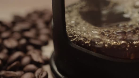 Pouring fresh coffee into a pot with coffee beans