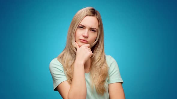 Thoughtful Woman Looking Aside with Pensive Expression Againast Blue Background