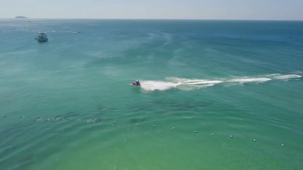 Aerial Tracking Fly Over a Tourist in a Resort Riding a Fast Jetski on Summer