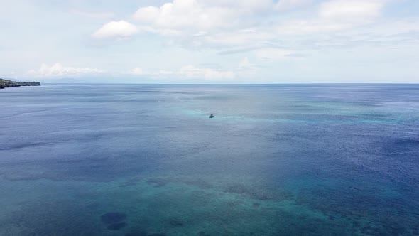 Small dive boat on stunning coral reef on blue and turquoise ocean water at remote secluded tropical