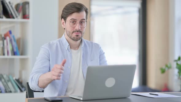 Thumbs Down By Man in Glasses with Laptop in Office