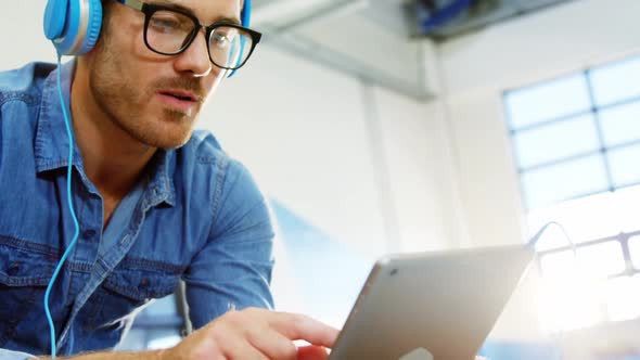 Business executive listening to music on digital tablet